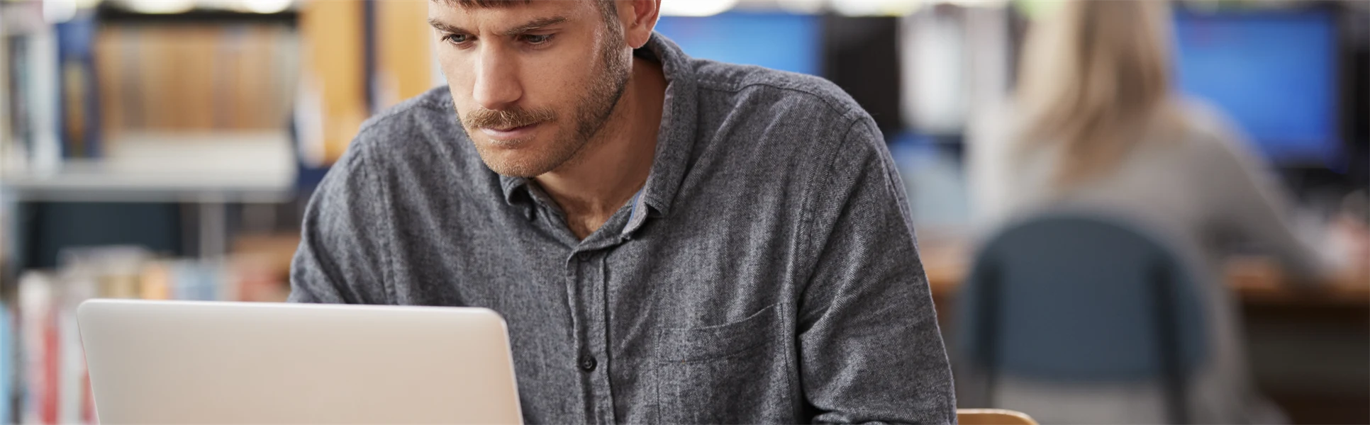 Manlig student skriver på dator i studiemiljö