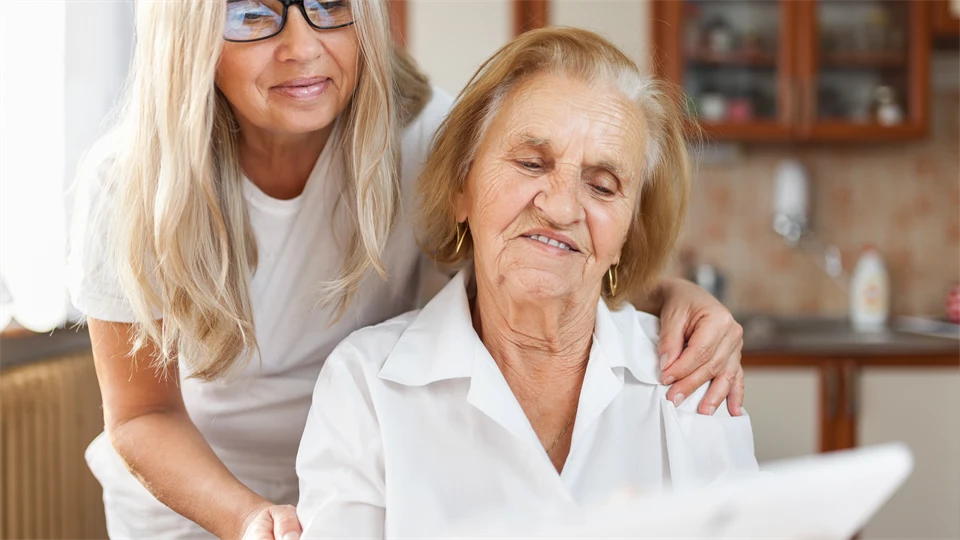 Younger woman looking at a screen older woman is holding.